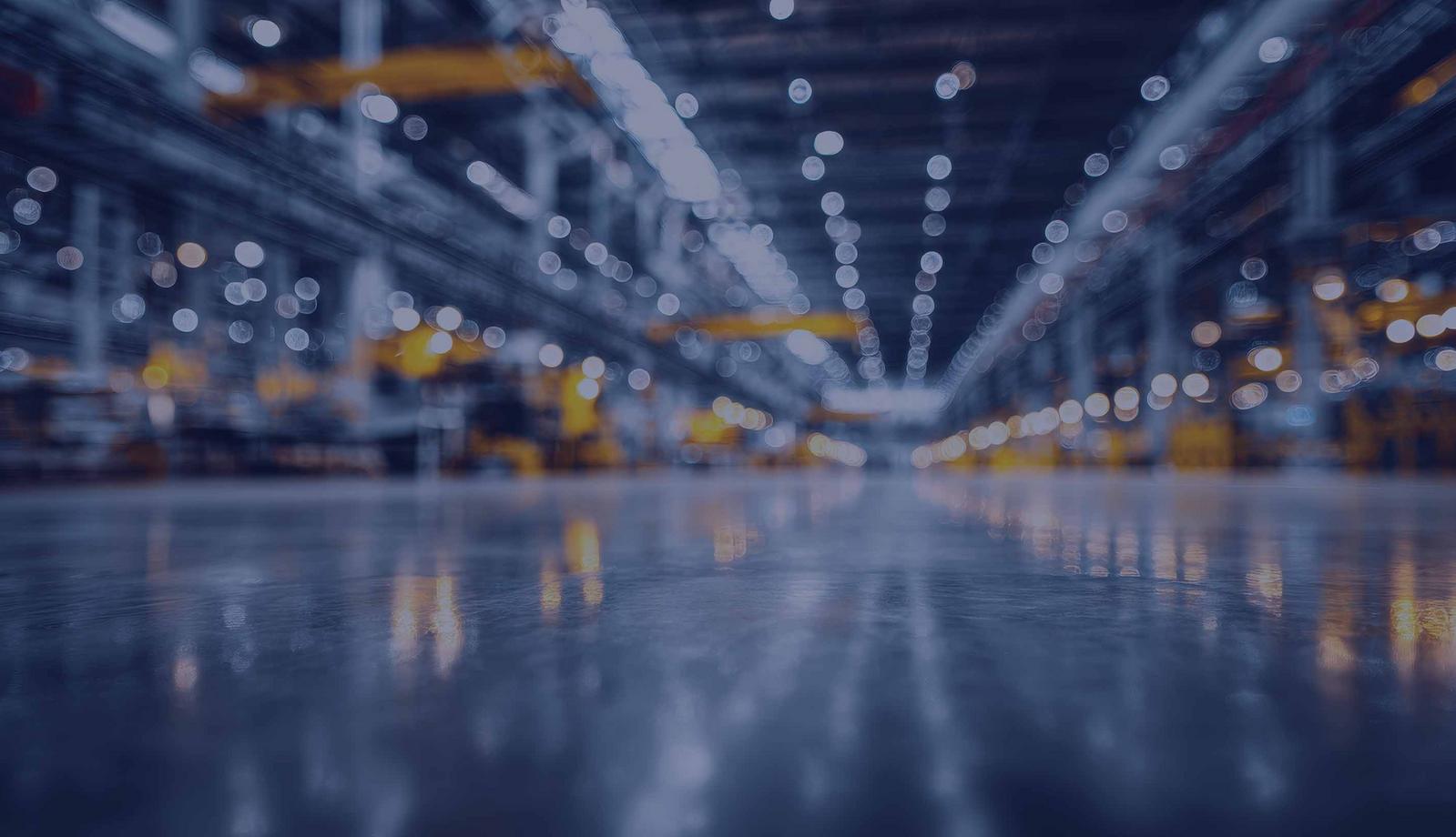 Blurred warehouse interior with shiny floor and distant lights.